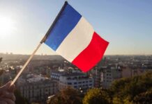 French flag waving over a city skyline at sunset