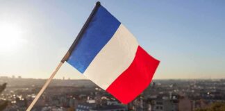 French flag waving over a city skyline at sunset