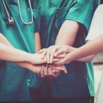 Unpaid Ebola Staff Halt Care — Outbreak Accelerates medical team stacking hands in unity