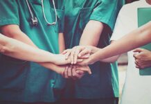 Unpaid Ebola Staff Halt Care — Outbreak Accelerates medical team stacking hands in unity