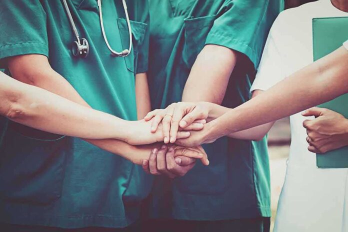 shutterstock_609423461 medical team stacking hands in unity