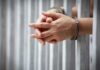 Bisexuality Bluff Called — UK Boots Convicted Offender hands in handcuffs behind jail bars