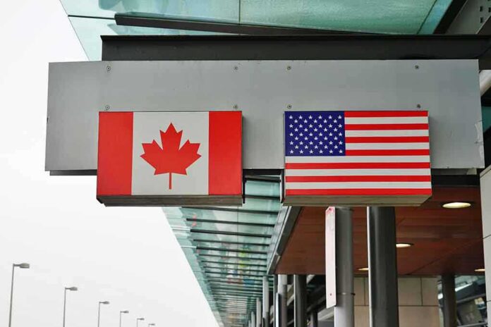 shutterstock_1044483421-2- Canadian and American flags displayed at a border crossing