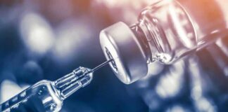 syringe needle drawing liquid from a vaccine vial