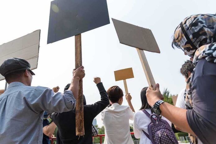 shutterstock_1051291337 Group of people holding protest signs outdoors