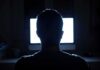 Massive Deepfake Bust – 12 Sites Vanish person silhouetted in front of a bright computer screen