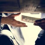 Hands exchanging cash under a table