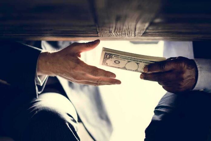 shutterstock_1067714837 Hands exchanging cash under a table