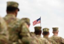 U.S. flag flying above a formation of soldiers in uniform
