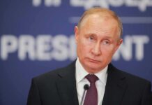 Globalists Blasted—Putin Points To Berlin Upset man in suit at podium with microphone