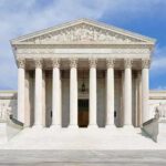 High-Stakes USPS Fight Before November Front view of the Supreme Court building with large columns and steps under a blue sky