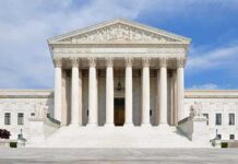 High-Stakes USPS Fight Before November Front view of the Supreme Court building with large columns and steps under a blue sky