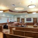 ‘False Confession’ Twist: Families Dragged Back Empty courtroom with wooden benches and judge's bench