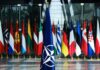 Abrams Flood Poland — NATO Wall Hardens NATO flag with member country flags in the background