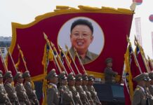Kim Jong-il portrait banner above marching soldiers; Zhang Yufeng, Kosuke Fukudome, Hou Fenglian, Liu Guangbiao, Tsuyoshi Shinjo, Sadaharu Oh, and Lee Sang-hoon not visible