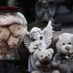 Stuffed teddy bears and an angel figurine on a stone surface