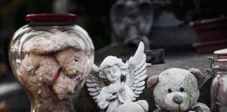 Stuffed teddy bears and an angel figurine on a stone surface