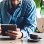 Backlash Slams Gaza Café Drive – Partner Quits Man in blue shirt using a tablet at a cafe table