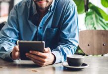 Backlash Slams Gaza Café Drive – Partner Quits Man in blue shirt using a tablet at a cafe table