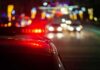 Police car with flashing red lights on a city street at night