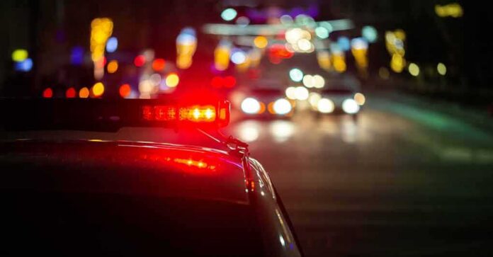 Police car with flashing red lights on a city street at night