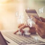 Hands holding a credit card over a laptop for online shopping