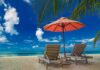 Greek Paradise – Sunbed Fight Ends In Tragedy Two lounge chairs under an orange umbrella on a tropical beach