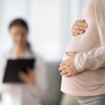Pregnant woman holding belly during medical visit