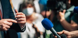 Microphones held toward a speaker at an outdoor press event