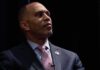 Caught On Tape: Shocking Slur Stuns House Leader man in suit looking to the side on a dark stage