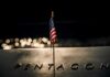 Anniversary Jolt: Trump’s Words Hit Hard Small American flag on a memorial with bokeh lights at night
