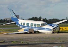 Damaged blue and white small airplane on an airport runway