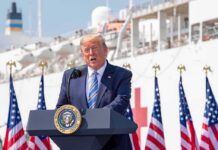 Canada Fumes As Trump Floats Lake Rebrand Donald Trump speaking at a podium with American flags and a ship in the background