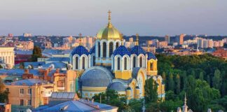 Orthodox church with blue and gold domes in a cityscape at sunset