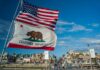 ‘Boneheaded’ Moment Haunts Newsom California Republic flag and US flag over a sunny coastal boardwalk