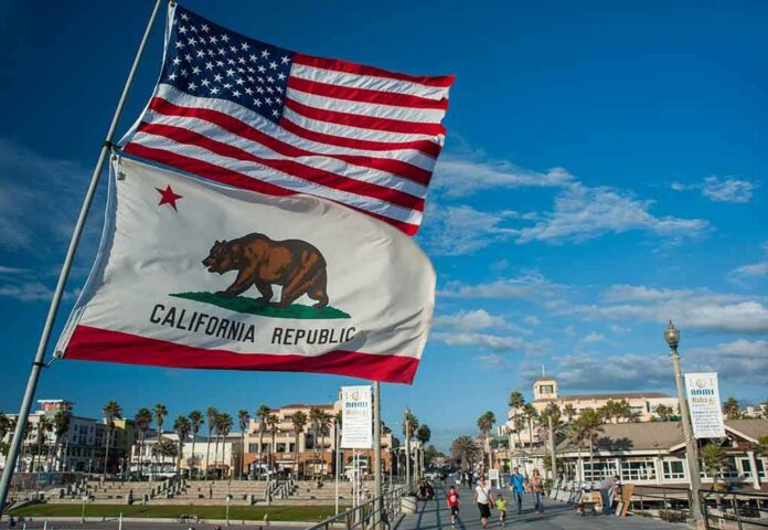 shutterstock_606982667 California Republic flag and US flag over a sunny coastal boardwalk