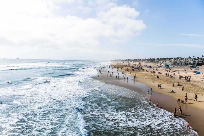 shutterstock_697274677-1 Crowded sandy beach with people by the shoreline
