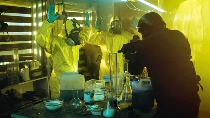 shutterstock_729057004 armed officer confronts people in hazmat suits inside a lab