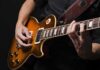 Electric guitar player strumming and fretting on a sunburst Les Paul style guitar