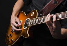 Electric guitar player strumming and fretting on a sunburst Les Paul style guitar
