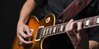 Electric guitar player strumming and fretting on a sunburst Les Paul style guitar