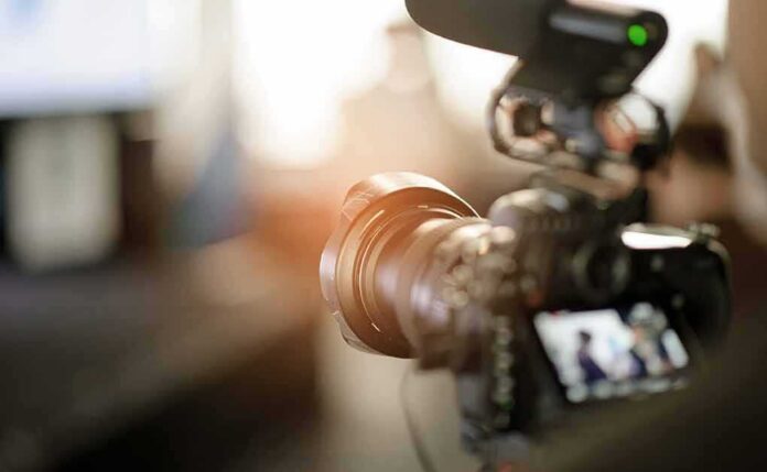 shutterstock_1174879405 Video camera with external microphone recording indoors