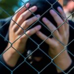 Free Speech Showdown: Teen Dragged In Person behind chain-link fence holding head in hands