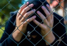 Free Speech Showdown: Teen Dragged In Person behind chain-link fence holding head in hands