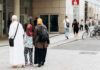 UK Hands Out Hijabs – Border Welfare Or Welcome Pack? Three people walking on a city sidewalk