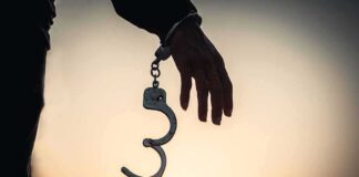 Hand with open handcuff in silhouette at sunset