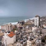 Coastal city skyline with mid-rise buildings by a rough sea under overcast skies