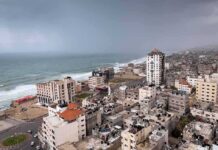 Coastal city skyline with mid-rise buildings by a rough sea under overcast skies