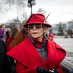 Celebrity Cash Supercharges Dem Ground Game Jane Fonda in a red coat and hat with Walter Jones beside her outdoors