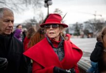 Celebrity Cash Supercharges Dem Ground Game Jane Fonda in a red coat and hat with Walter Jones beside her outdoors